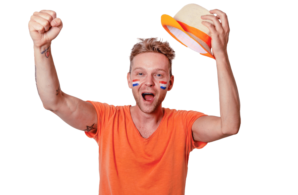 Man met oranje shirt en nederland vlaggetjes op zijn gezicht die juicht met een hoedje in zijn hand.