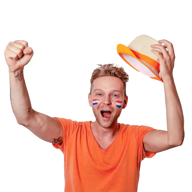 Man met oranje shirt en nederland vlaggetjes op zijn gezicht die juicht met een hoedje in zijn hand.