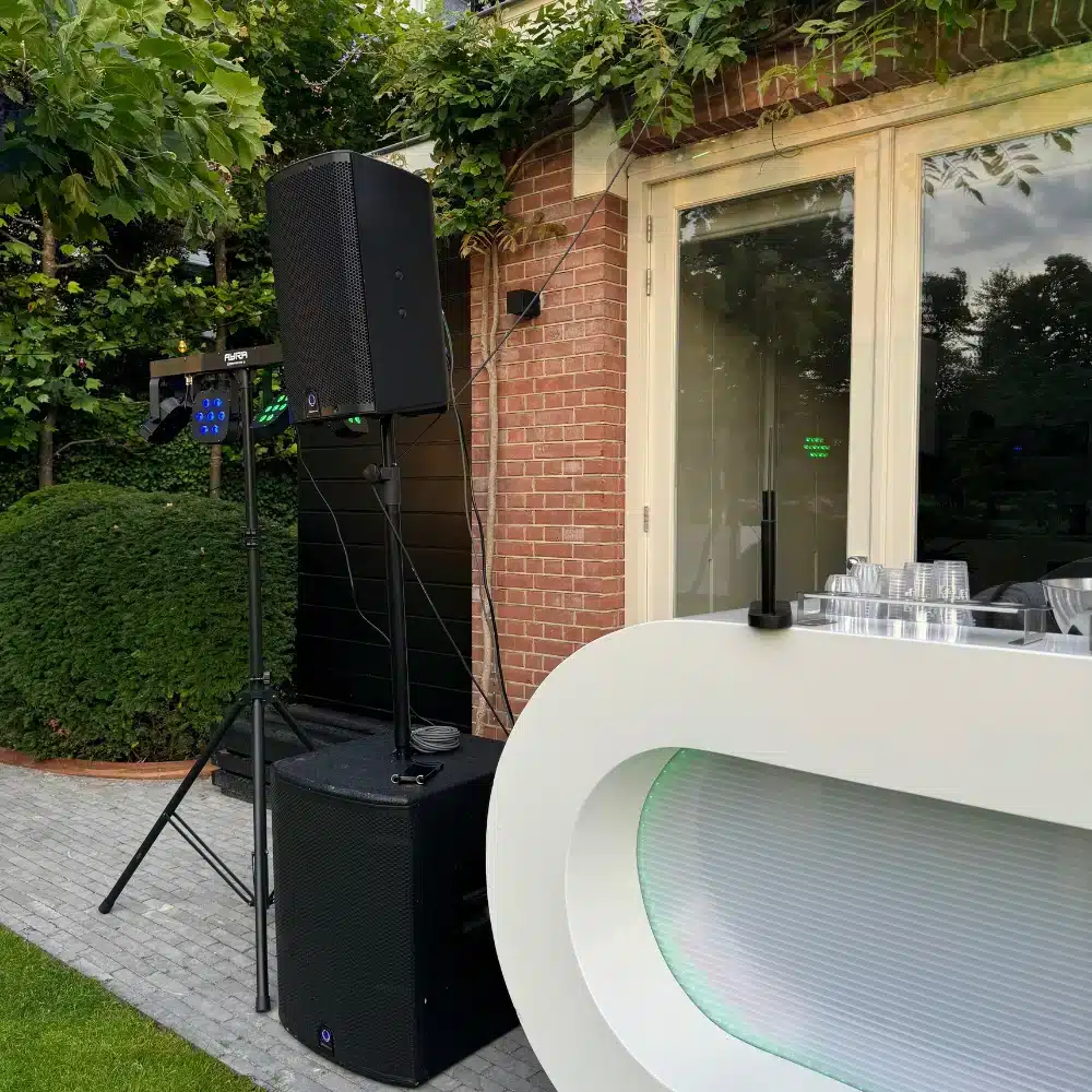 Geluidsinstallatie op een tuinfeest speakers en subwoofer naast een dj-booth