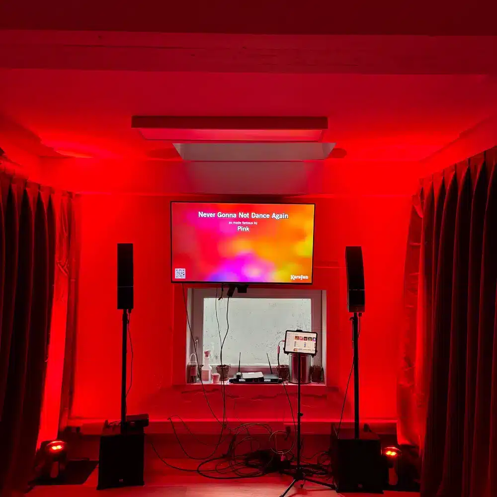 Karaoke set met scherm en speakers in een rode ruimte